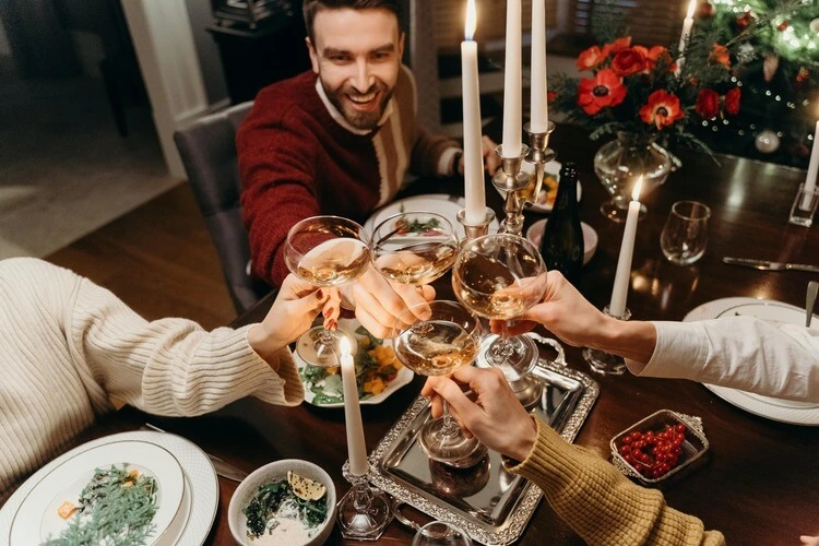 Group of friends toasting with glasses of champagne at a festive holiday dinner table