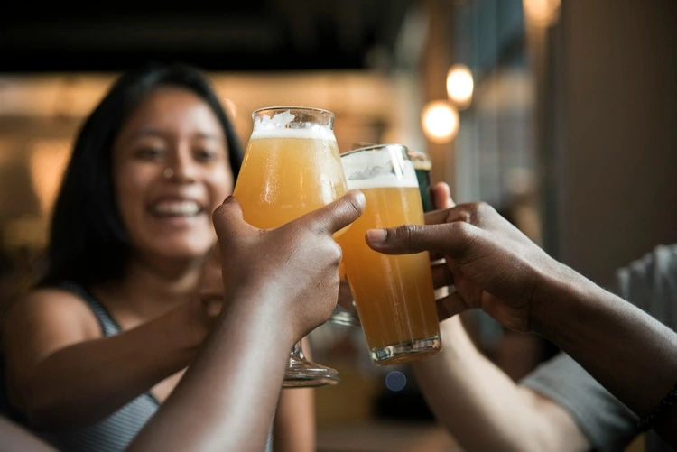 Three people raising glasses of beer in a celebratory toast, smiling and enjoying the moment.