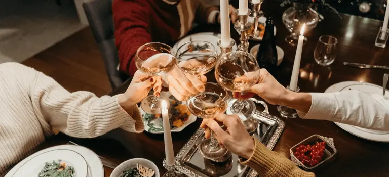 Group of friends toasting with glasses of champagne at a festive holiday dinner table