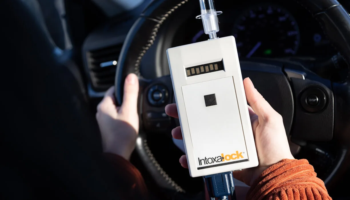 Close-up of an Intoxalock ignition interlock device held by a person inside a car